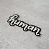 A hand-lettered vinyl sticker for humans of all sorts. Great for decorating your laptop, water bottle, locker, car, or whatever! By Em Dash Paper Co.